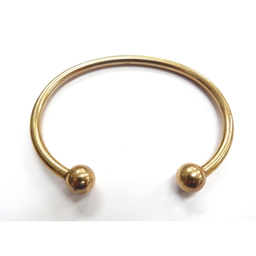 6024 - A 9ct gold bangle with ball terminals, 24.2g