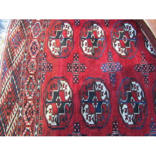 1020 - A geometric design red ground rug, two rows of lozenges, multiple borders and tasselled ends, 155cm ... 