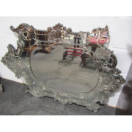 1043 - An ornate hand-crafted Venetian style modern glass wall mirror, with bevelled cut frame in foliate a... 