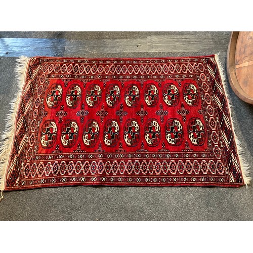 1020 - A geometric design red ground rug, two rows of lozenges, multiple borders and tasselled ends, 155cm ... 