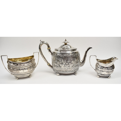 8013 - A George III matched silver three piece tea set of highly ornate form with all-over engraved and emb... 