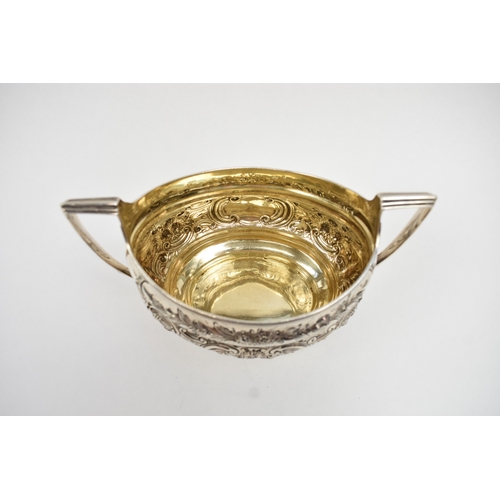 8013 - A George III matched silver three piece tea set of highly ornate form with all-over engraved and emb... 