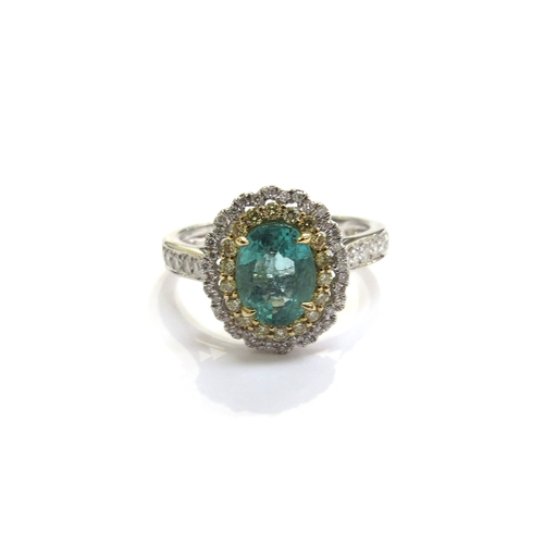 6122 - A 14ct white gold emerald and diamond ring the central oval emerald framed in turn by yellow and whi... 