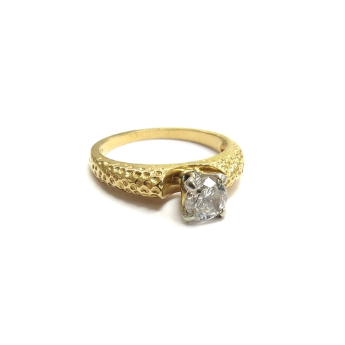 6058 - A diamond solitaire ring in four claw mount within a textured shank, 18ct. Size M/N, 4g