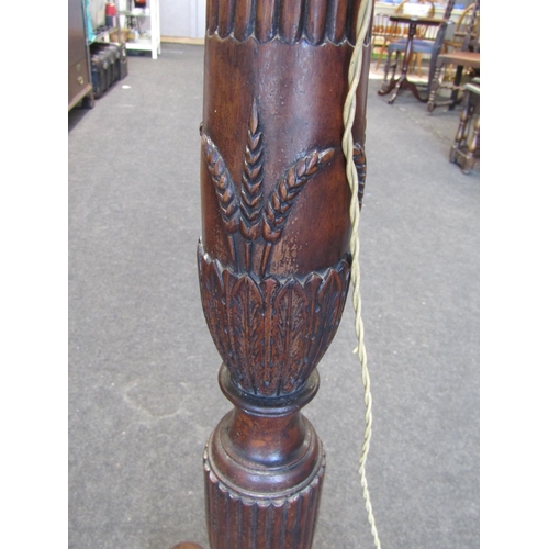 1010 - A carved oak standard lamp on tripod legs with ball in claw feet