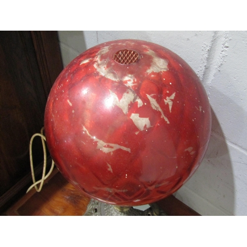 1037 - A table lamp, the red globular glass shade over an ornate brass base