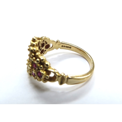 6040 - An 18ct gold ruby and diamond cluster ring, the central round ruby framed by diamonds with three rub... 