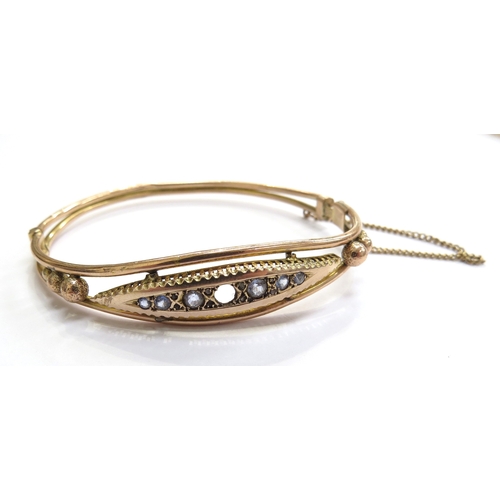 6011 - A 9ct gold hinged bangle, clasp a/f, set with pale blue sapphires (one missing), 6.4g