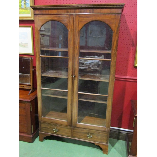 4044 - A Georgian mahogany bookcase, two arch top glazed doors and two drawers over bracket feet, with key,... 