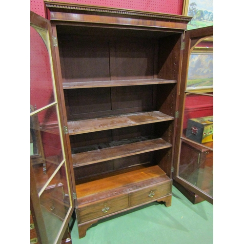 4044 - A Georgian mahogany bookcase, two arch top glazed doors and two drawers over bracket feet, with key,... 