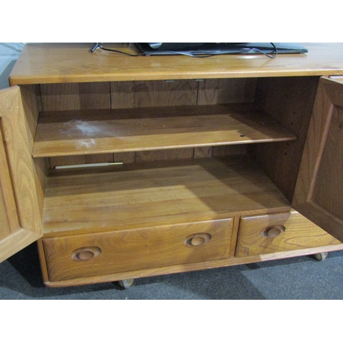 1007 - An Ercol Windsor light elm sideboard, raised on castors, three cupboards over two drawers, 76cm tall... 