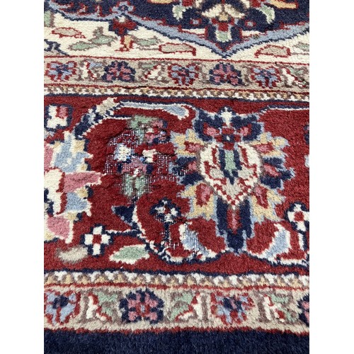 4452 - A red and blue ground Persian wool rug, central floral medallion, multiple borders, tasselled ends, ... 