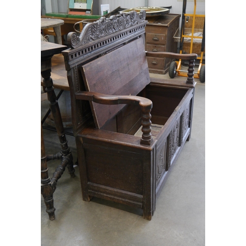 2001 - An 18th Century carved oak settle, three heraldic panels to back and front, rising seat, outswept ar... 