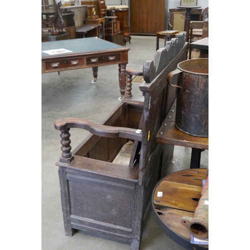 2001 - An 18th Century carved oak settle, three heraldic panels to back and front, rising seat, outswept ar... 
