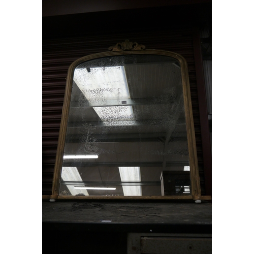 2064 - A Victorian Gesso framed over mantle mirror with a shaped finial, on porcelain bun feet, foxing to m... 