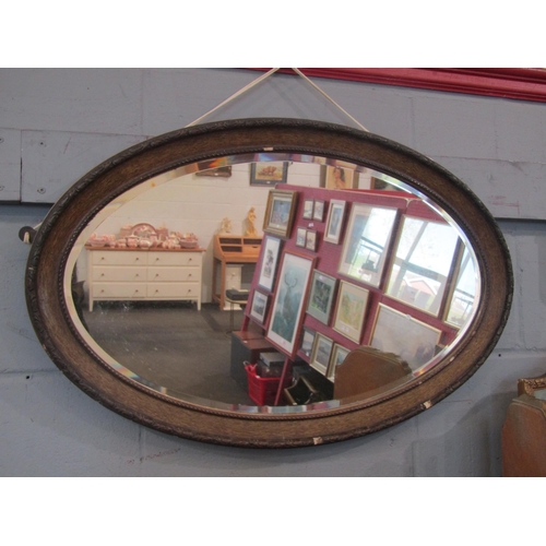 1075 - An oval wall mirror with mahogany frame and plaster edge, some a/f, 49cm x 77cm total