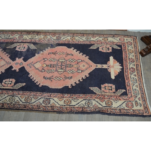 8553 - A 20th Century hand-woven runner rug with blue and red geometric pattern, worn in areas, 315cm x 110... 