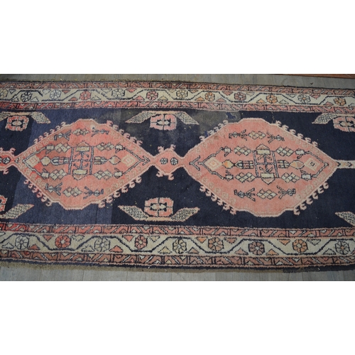 8553 - A 20th Century hand-woven runner rug with blue and red geometric pattern, worn in areas, 315cm x 110... 