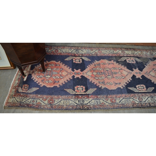 8553 - A 20th Century hand-woven runner rug with blue and red geometric pattern, worn in areas, 315cm x 110... 