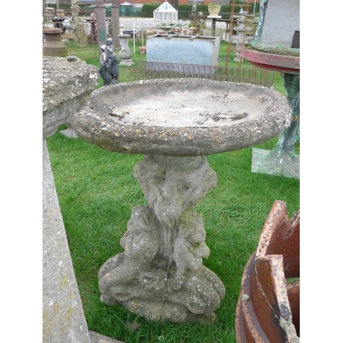 8025 - A reconstituted birdbath on fish and cherub base, 61cm diameter x 81cm high