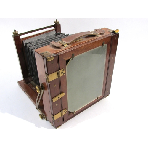 7004 - A mahogany and brass half-plate field camera with unnamed brass lens, black bellows in good order, w... 