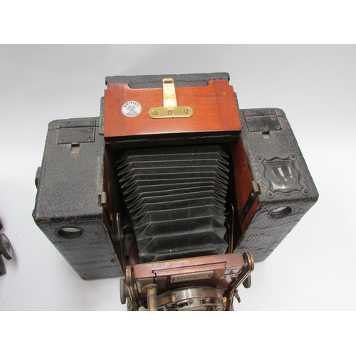 7011 - A Sanderson Hand and Stand plate camera with brass fittings and mahogany body, housed in a black lea... 