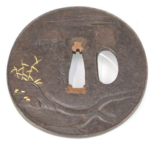 7019 - A circular iron tsuba decorated in takazogan and shishiaibori depicting a man standing by a river lo... 