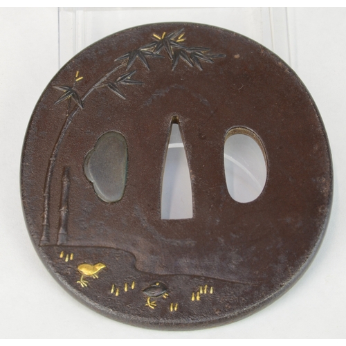 7027 - An oval iron tsuba decorated in takazogan gold and shibuichi to depict hens and chicks beneath bambo... 