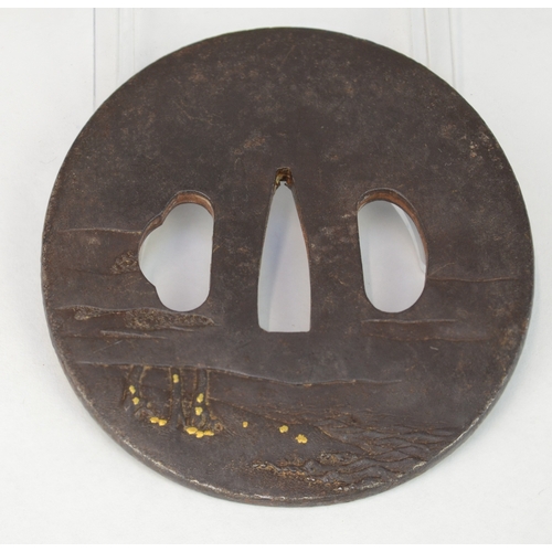 7029 - A circular iron tsuba decorated in takazogan highlighted with gold and shibuichi depicting a man sea... 