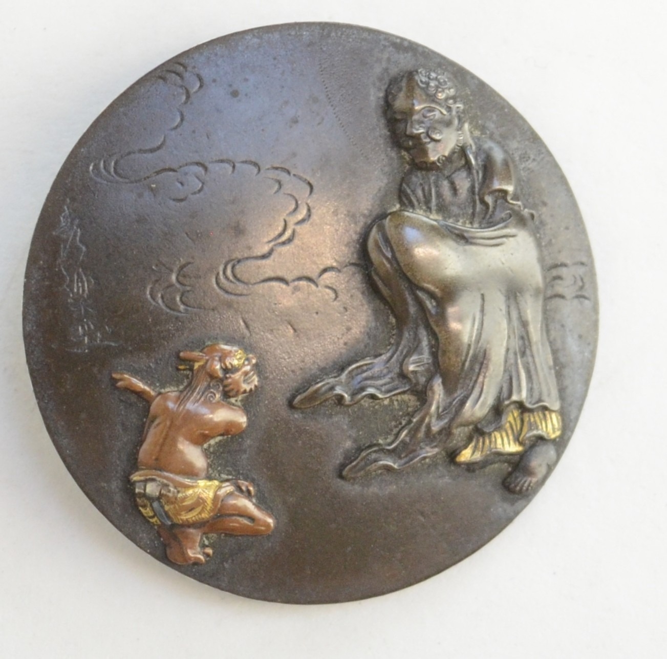 A shibuichi kagamibuta netsuke depicting an oni (in copper and gold ...