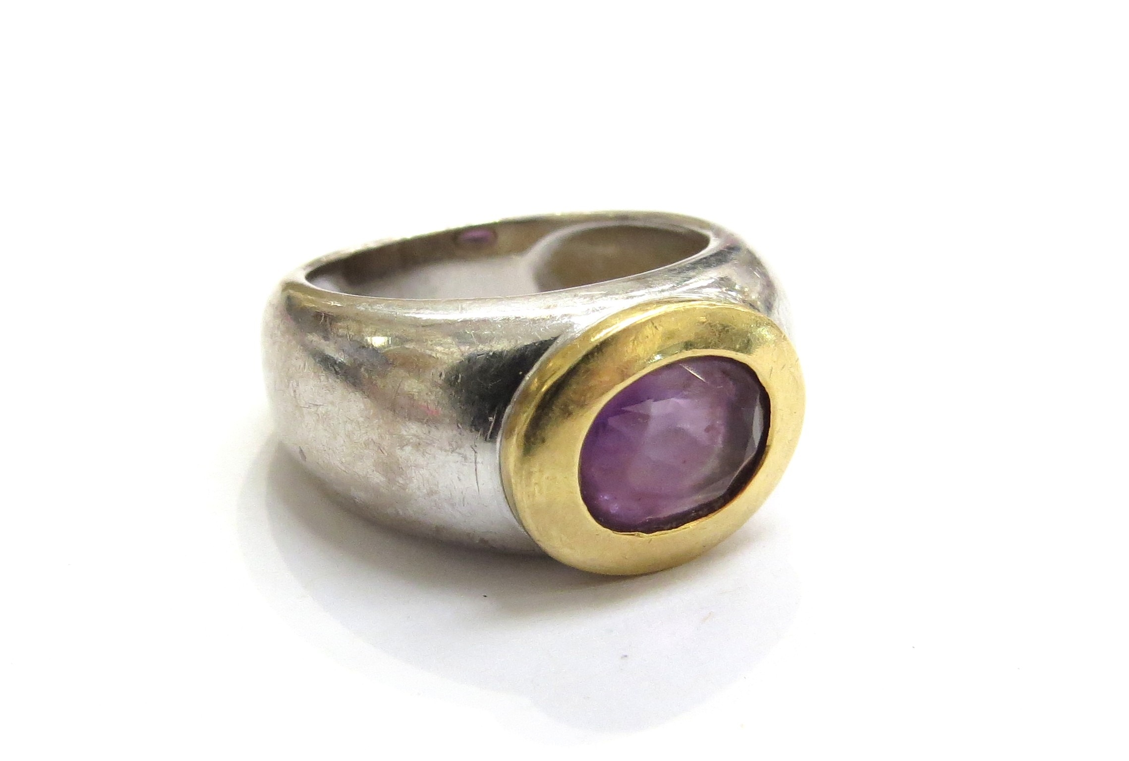 A white gold wide band with oval amethyst in yellow gold rubover ...