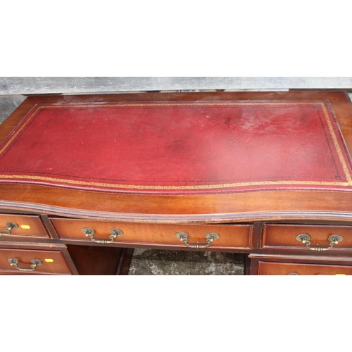 617 - A mahogany serpentine front pedestal desk with tooled leather top, fitted nine drawers, on block bas... 