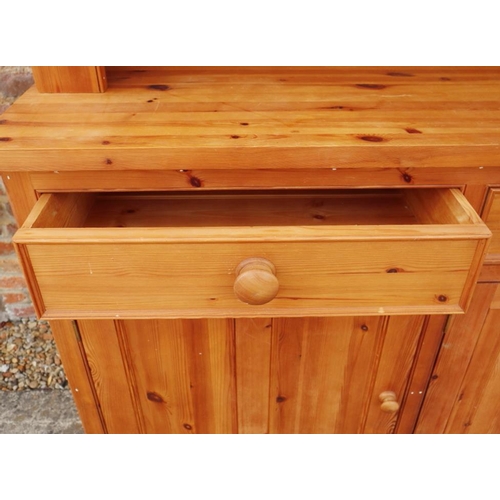 689 - A waxed pine dresser with plate shelves over three drawers and cupboards, on block base