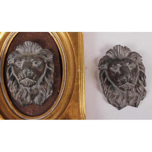 128 - A pair of cast iron lions' heads, one in gilt frame