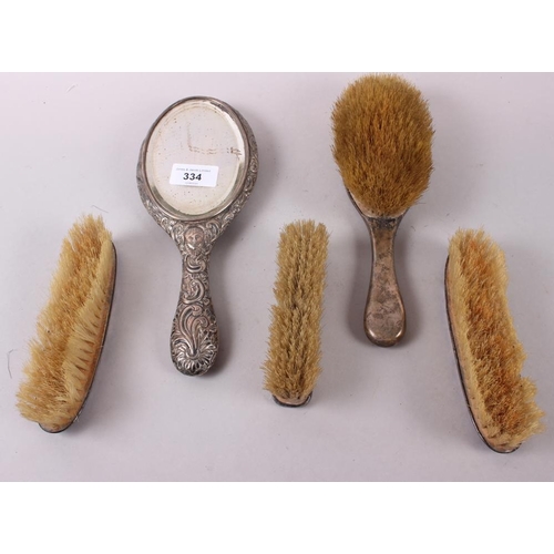 334 - Four silver dressing table brushes and a silver hand mirror