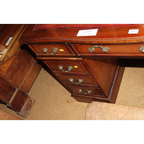 617 - A mahogany serpentine front pedestal desk with tooled leather top, fitted nine drawers, on block bas... 