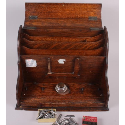 145 - An early 20th century oak stationary cabinet with an associated glass inkwell and a number of dip pe... 