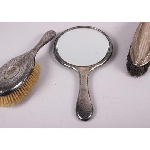 258 - A silver dressing table mirror with planished decoration, a matching hair brush and one other silver... 