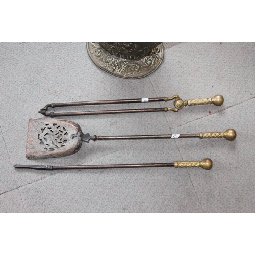 112 - An embossed brass coal bucket and a set of steel fire irons with cast brass handles