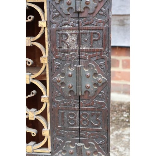 534 - A 19th century carved oak corner cupboard, inscribed RTP 1883, with wrought iron grille door, 20