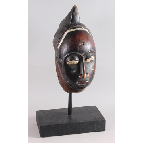 152 - A West African carved hardwood tribal mask, on ebonised stand, 13 1/4