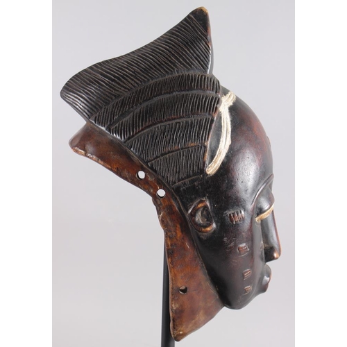 152 - A West African carved hardwood tribal mask, on ebonised stand, 13 1/4