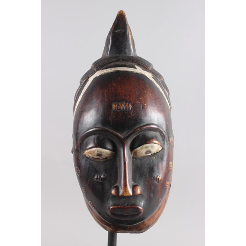 152 - A West African carved hardwood tribal mask, on ebonised stand, 13 1/4