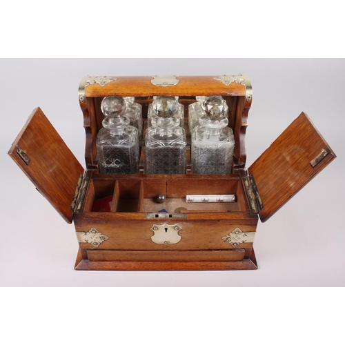 166 - An early 20th century oak tantalus with silver plated mounts, fitted two hinged flaps enclosing fitt... 