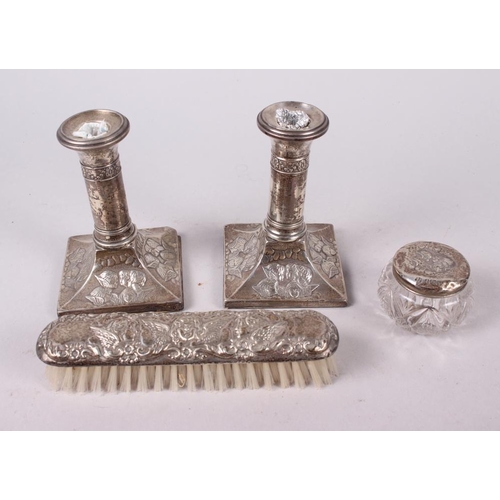 315 - A pair of squat silver candlesticks embossed cherubs' heads, and a similar hand mirror, pin jar and ... 