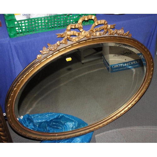 593 - An oval bevelled plate wall mirror, in gilt frame with ribbon surmount, 31