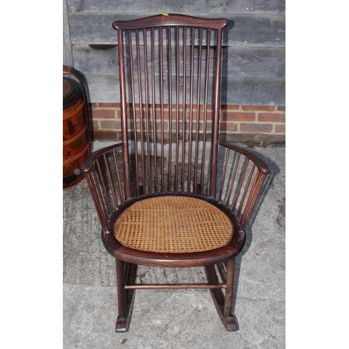 599 - A tall spindle back rocking chair with caned seat panel