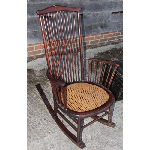 599 - A tall spindle back rocking chair with caned seat panel