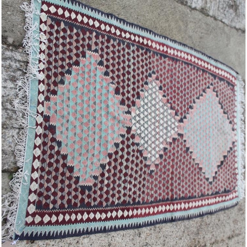 733 - A kelim rug decorated three lozenges on a red ground, 70