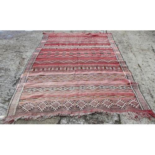 737 - A Moroccan tribal rug decorated bands of geometric ornament on a red ground, 106